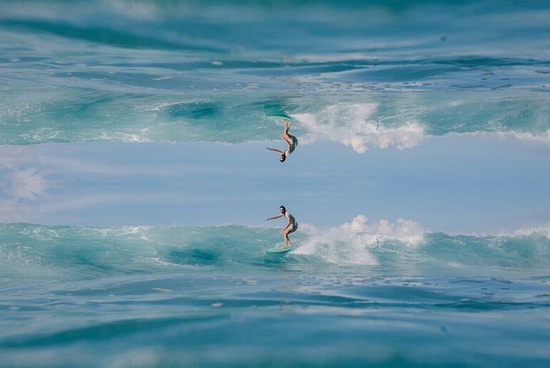 Horizontal mirror image effect on photo of man surfing small wave on blue surfboard made with photo editor