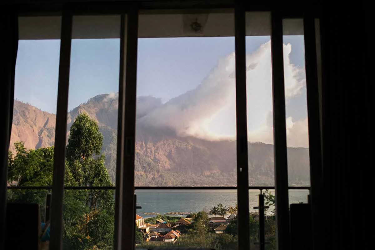 dark room with windows open looking out on a lake and mountain