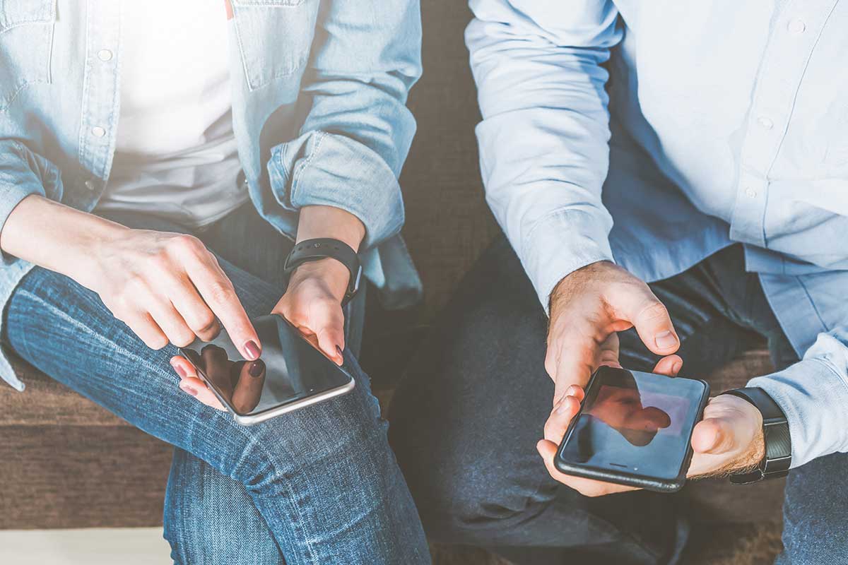 man and woman sitting looking at their phones