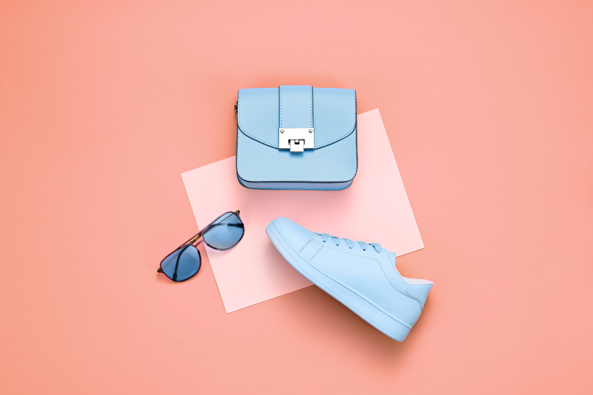 flat lay of a purse sunglasses and shoes on an orange background