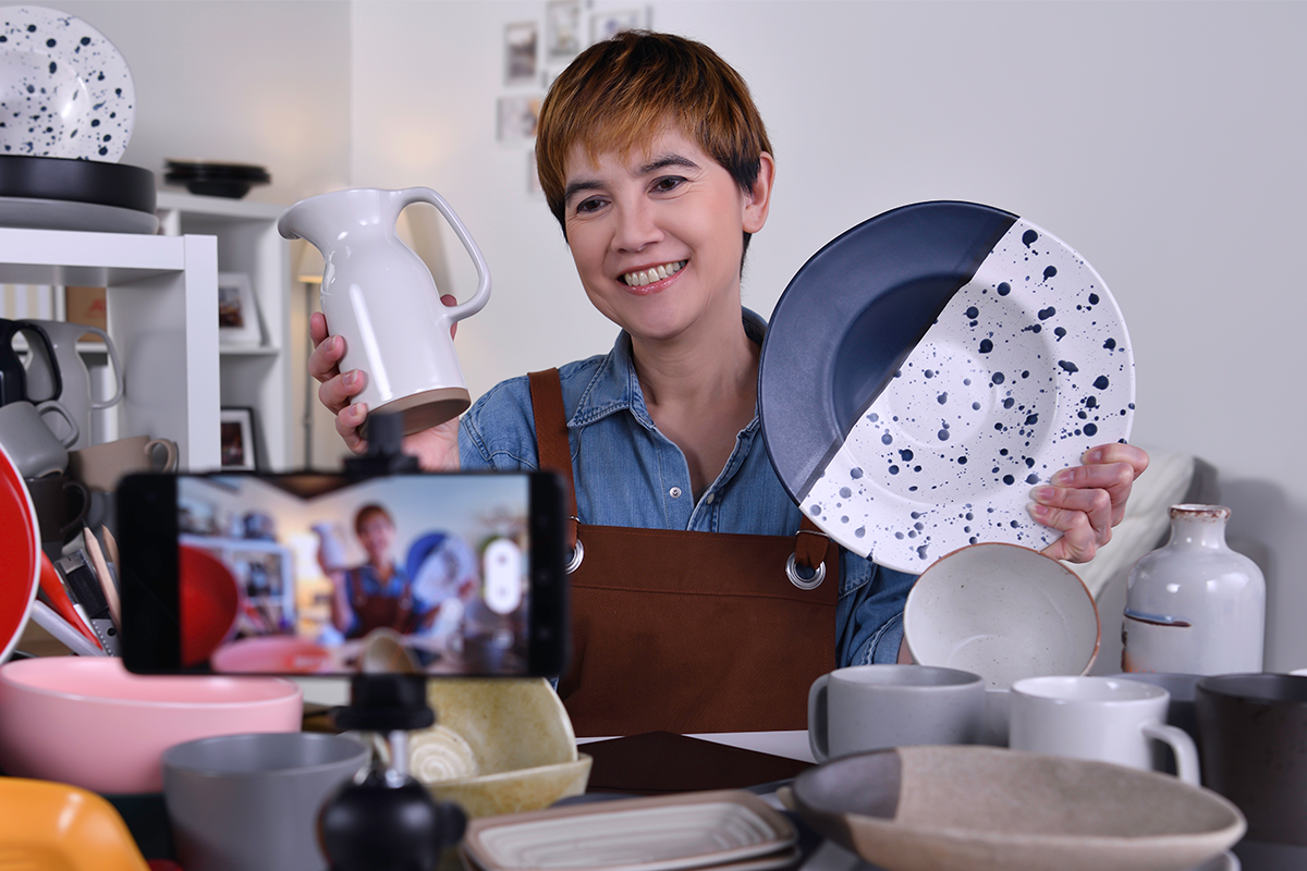 woman holding pottery in front of a camera while recording herself