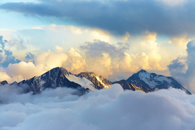 mountains peaking out through clouds at sunrise