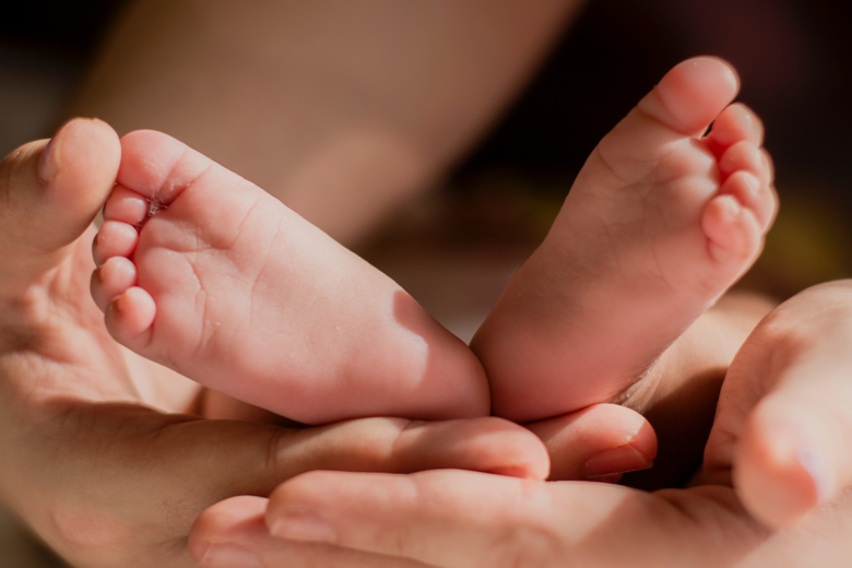 newborn baby photo idea of parent holding baby's feet in palm of hands