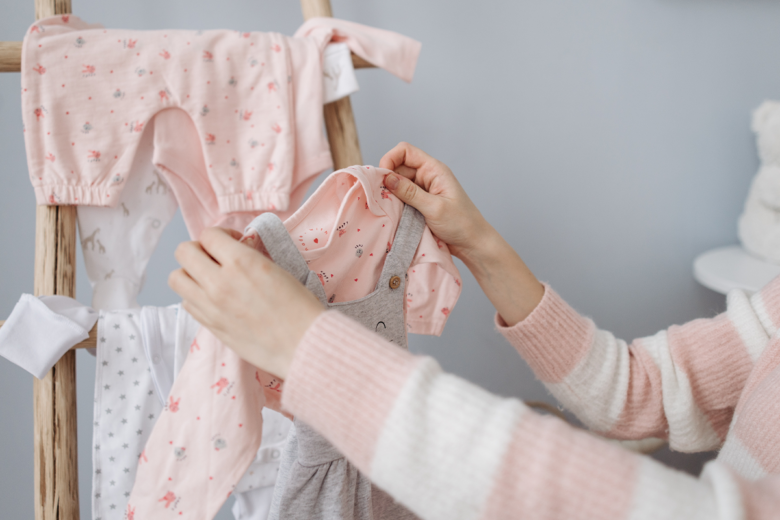 woman hanging baby girl clothes on a ladder shelf