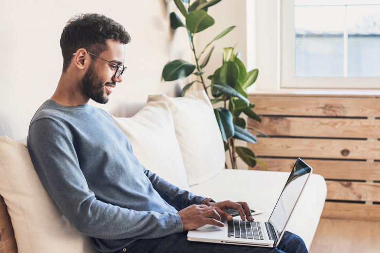 man sitting on couch with laptop on lap